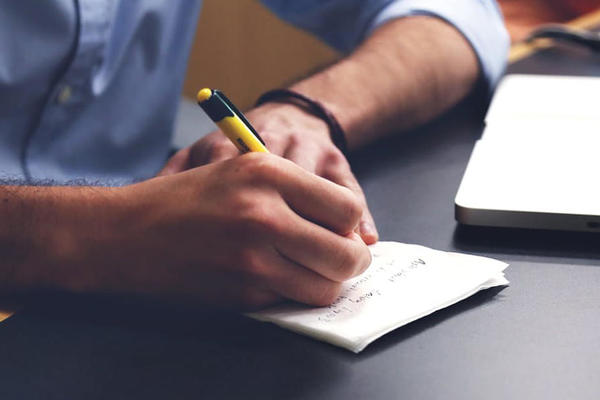 Person Writing on a Notebook